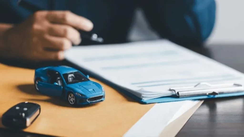 Contrato De Seguro De Veículos Sendo Analisado Com Miniatura De Carro E Chave Sobre A Mesa