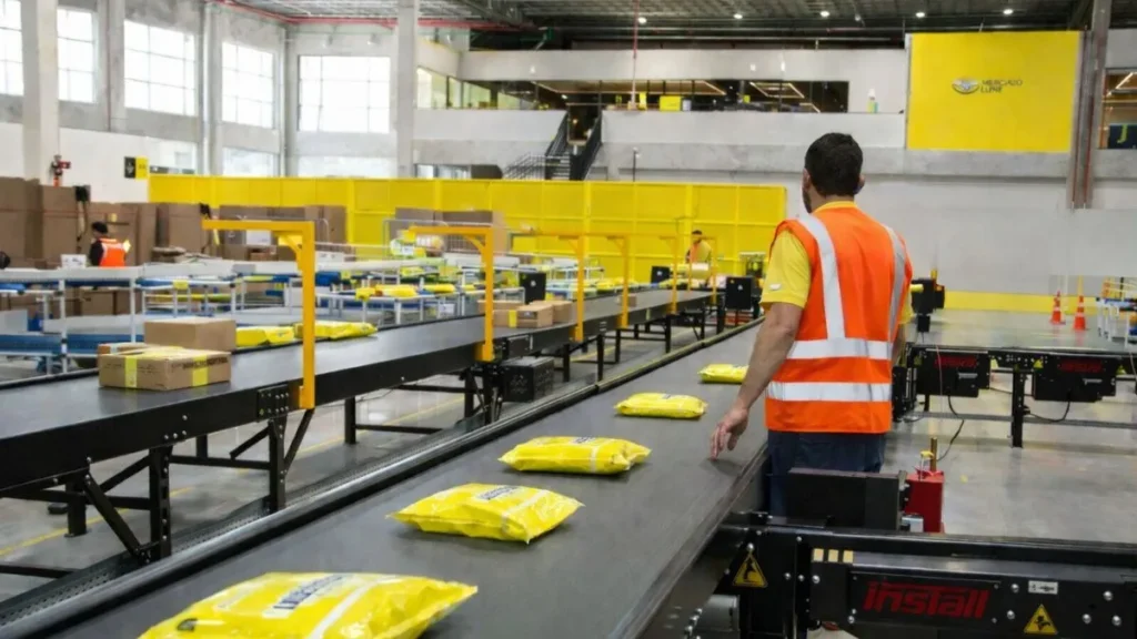 Mercado Livre Abre 500 Vagas Em Cajamar Com Oportunidades Para Moradores Da Região 3 Trabalhadores Atuam Em Centro De Distribuição Do Mercado Livre Em Cajamar, Com Pacotes Em Esteira Logística Durante Operação Interna.