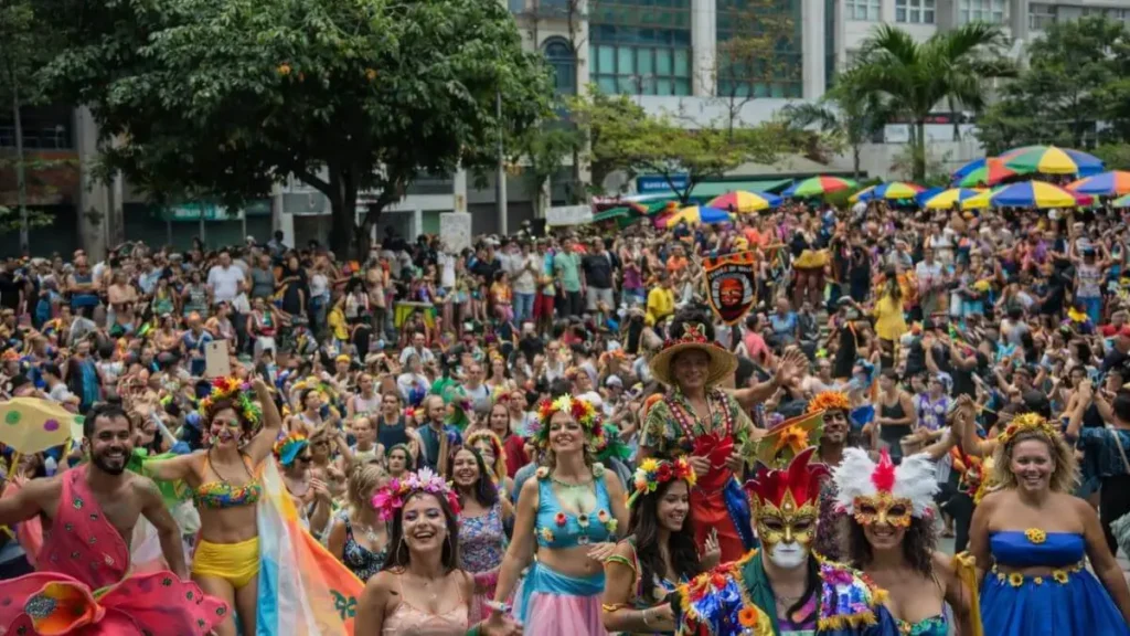 Multidão Participa De Bloco De Carnaval Em Via Urbana, Com Foliões Usando Máscaras Carnavalescas E Guarda-Chuvas Coloridos Ao Fundo Durante Desfile De Rua.
