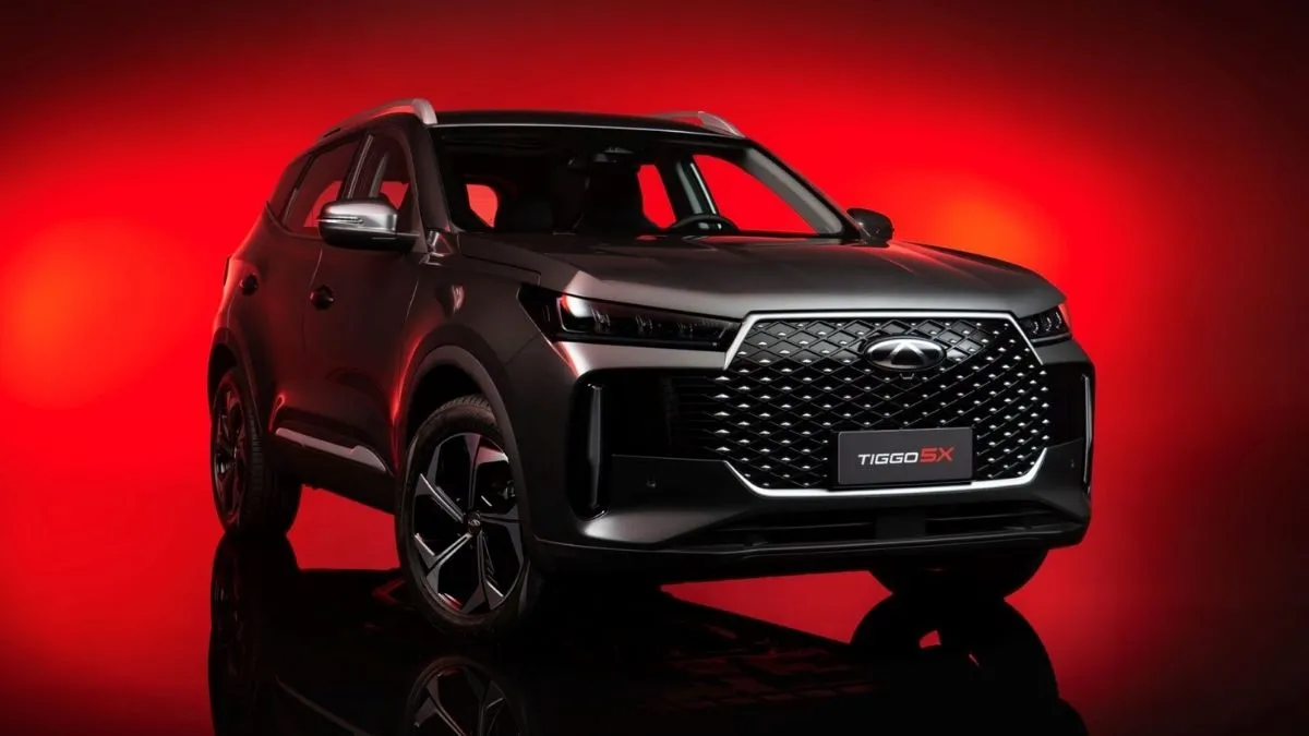 Caoa Chery Tiggo 5X 2027 em estúdio com fundo vermelho, destaque para a nova grade frontal tridimensional e faróis full LED