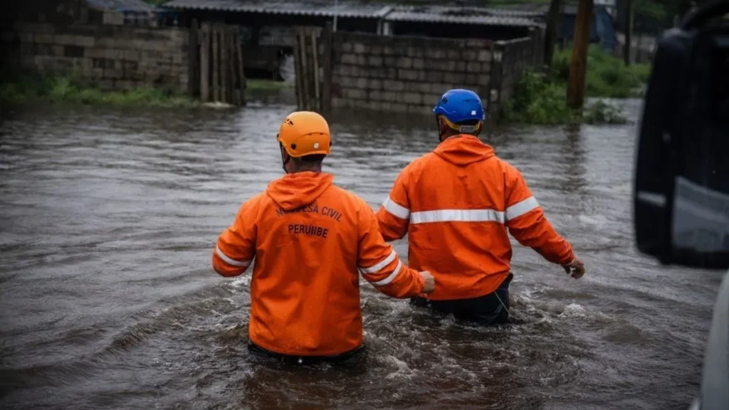 Agentes Da Defesa Civil Caminham Em Rua Alagada Em Peruíbe, No Litoral De São Paulo, Após Fortes Chuvas Que Deixaram Centenas De Desabrigados.