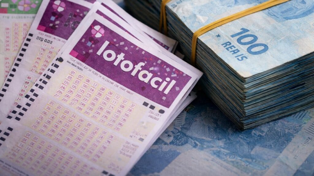 Bilhetes De Loteria Organizados Sobre Mesa Com Maço De Notas De Cem Reais Ao Fundo, Ilustrando Resultado Da Lotofácil E Prêmio Milionário.