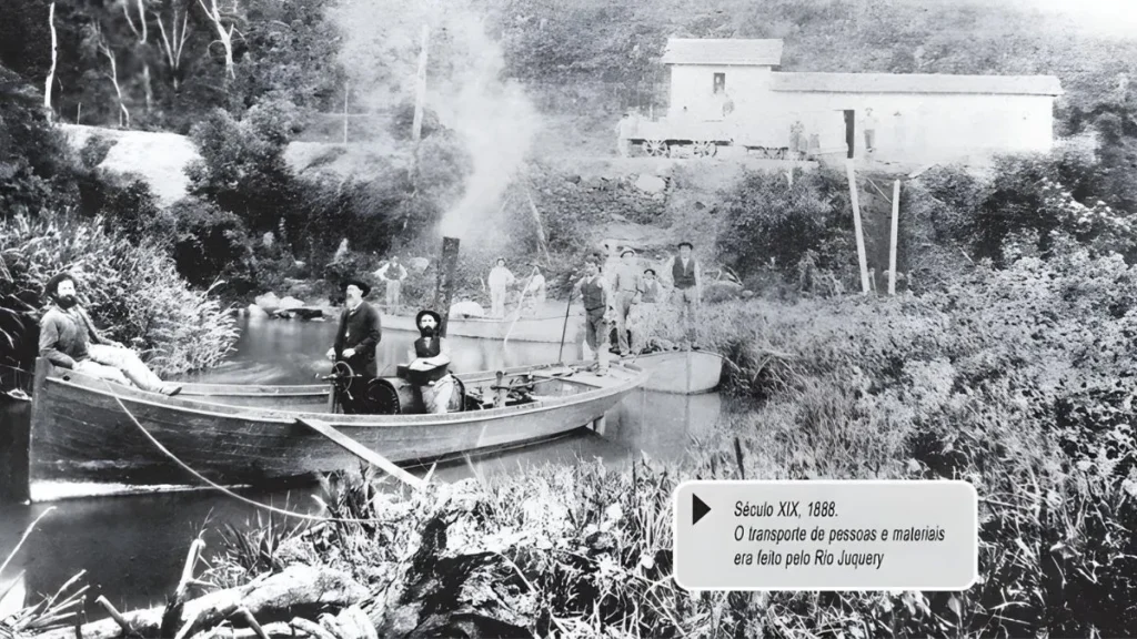 Barcos Transportando Pessoas E Materiais Pelo Rio Juquery Em 1888, Com Trabalhadores, Vegetação Densa E Construção Ao Fundo, No Início Da Formação De Caieiras