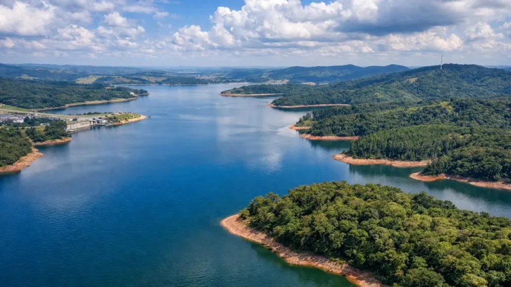 Vista Aérea Do Sistema Cantareira Em São Paulo Com Nível Elevado Após Chuvas De Verão, Mostrando Grande Volume De Água, Vegetação Ao Redor E Céu Parcialmente Nublado