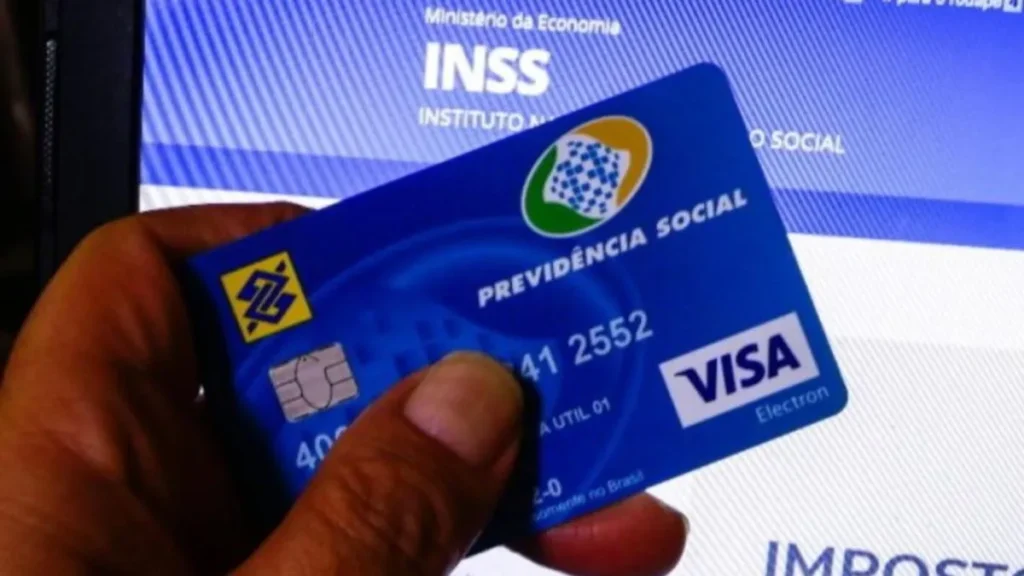 Cartão Da Previdência Social Do Inss Sendo Segurado Em Frente À Tela Do Site Oficial Do Instituto No Computador