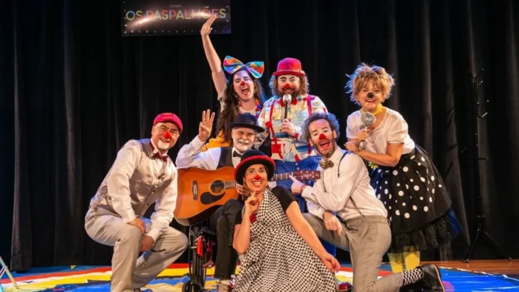 Artistas Circenses Caracterizados Como Palhaços Posam Juntos No Palco Durante Apresentação Da Semana Do Circo Em São Paulo, Com Figurinos Coloridos E Instrumentos Musicais.