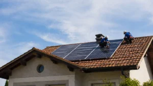 Técnicos Instalando Painéis Solares Em Telhado Residencial Durante O Dia, Com Céu Azul Ao Fundo