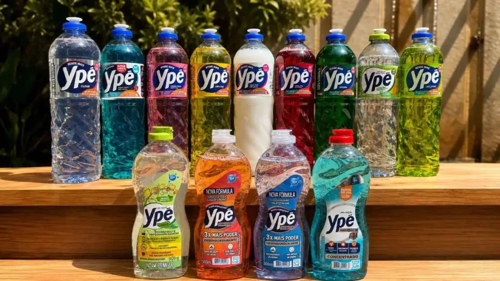 Linha De Produtos Ypê Organizada Sobre Prateleira De Madeira Em Ambiente Externo Iluminado, Com Detergentes Líquidos Coloridos E Embalagens De Limpeza Em Destaque.