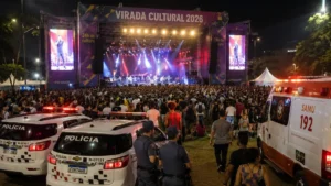 Palco Principal Da Virada Cultural 2026 Durante Show Noturno Em São Paulo, Com Grande Público Acompanhando A Apresentação Enquanto Viaturas Da Polícia Militar E Ambulância Do Samu Permanecem De Prontidão Na Área Do Evento.