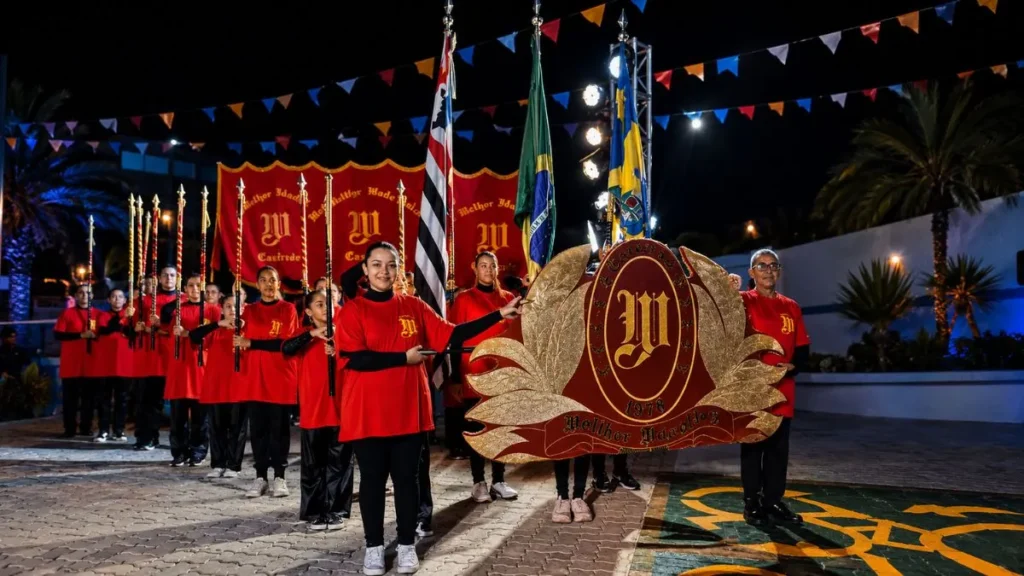 Tradição, Música E Clima De Encontro Marcam Os Próximos Dias Da Festa De Santo Antônio Em Caieiras 1 Fanfarra De Caieiras Se Apresenta Na 71ª Festa De Santo Antônio De Caieiras, Com Integrantes Em Uniforme Vermelho, Bandeiras E Estandarte Em Destaque Durante Apresentação Noturna.