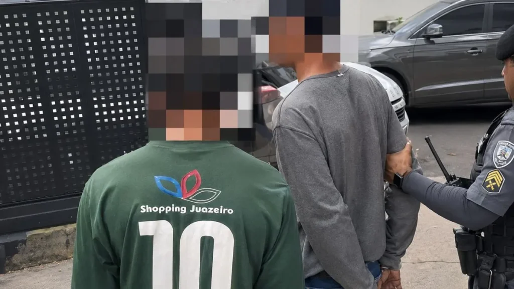 Dois Homens Com Rostos Pixelados São Acompanhados Por Policial Durante Ocorrência Em Área Urbana.