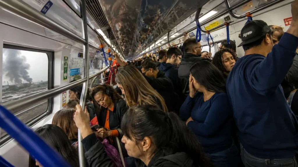 Incêndio Perto Da Linha 7-Rubi Trava Trens, Afeta Água Branca E Complica Viagem Até Barra Funda 1 Passageiros Em Trem Lotado Da Linha 7-Rubi Aparecem Com Expressões De Cansaço E Preocupação Durante Atraso Provocado Por Incêndio Próximo À Ferrovia, Enquanto Fumaça É Vista Pela Janela.
