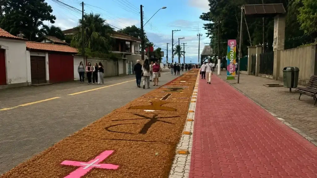 Tapetes De Serragem Unem Arte, Tradição E Dedicação Em Registros Feitos Por Moradores De Caieiras 1 Rua Em Bertioga Com Tapetes De Serragem Ao Centro E Pessoas Caminhando Ao Redor Durante Celebração De Corpus Christi.