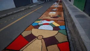 Tapete De Serragem Colorido Com Desenho De Cálice E Pomba, Formando Painel Artesanal Em Rua Decorada.