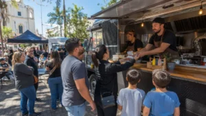 Food Truck Atende Moradores Em Praça Movimentada De Jundiaí Durante Evento Público Com Barracas, Mesas E Famílias No Local.