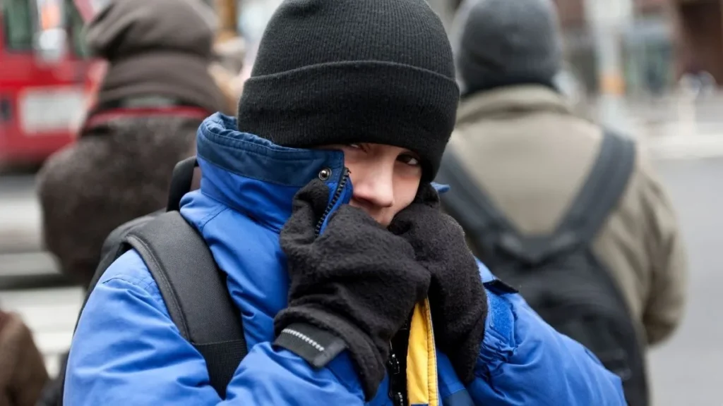 Frio Chega À Região E Pode Derrubar A Sensação Térmica Nos Próximos Dias 1 Pessoa Na Rua Usando Jaqueta De Frio Azul, Luvas E Gorro Preto Para Se Proteger Da Queda Brusca De Temperatura E Vento Gelado.