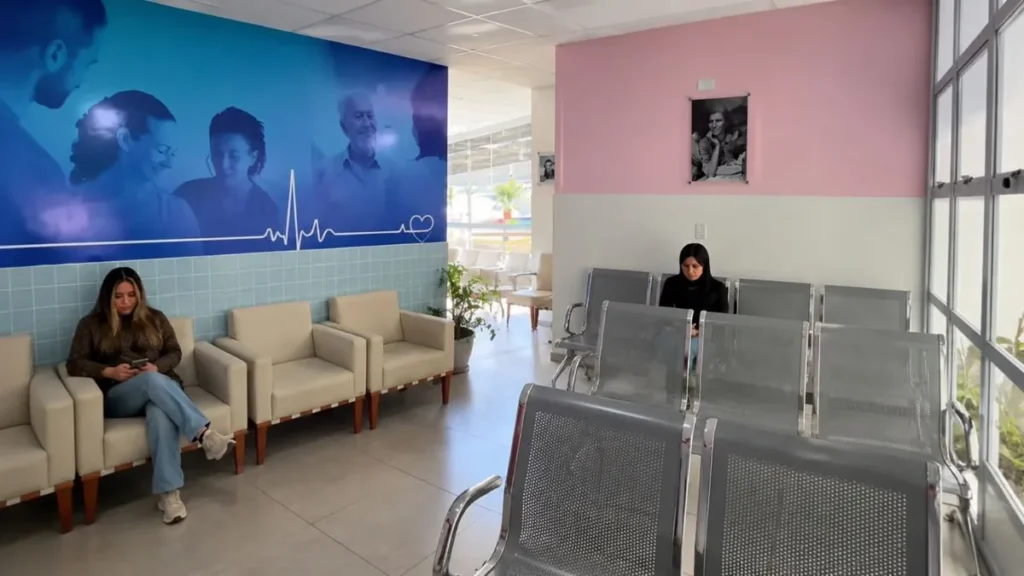 Faltas Em Consultas Viram Alvo De Campanha Em Caieiras E Expõem Reclamações Sobre A Saúde 4 Ala De Espera De Unidade De Saúde Em Caieiras, Com Poltronas Claras, Cadeiras Metálicas, Mural Azul Na Parede E Poucas Pessoas Sentadas Aguardando Atendimento
