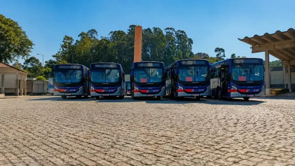 Cinco Ônibus Metropolitanos Da Viação Caieiras Alinhados Em Pátio Aberto Durante O Dia.