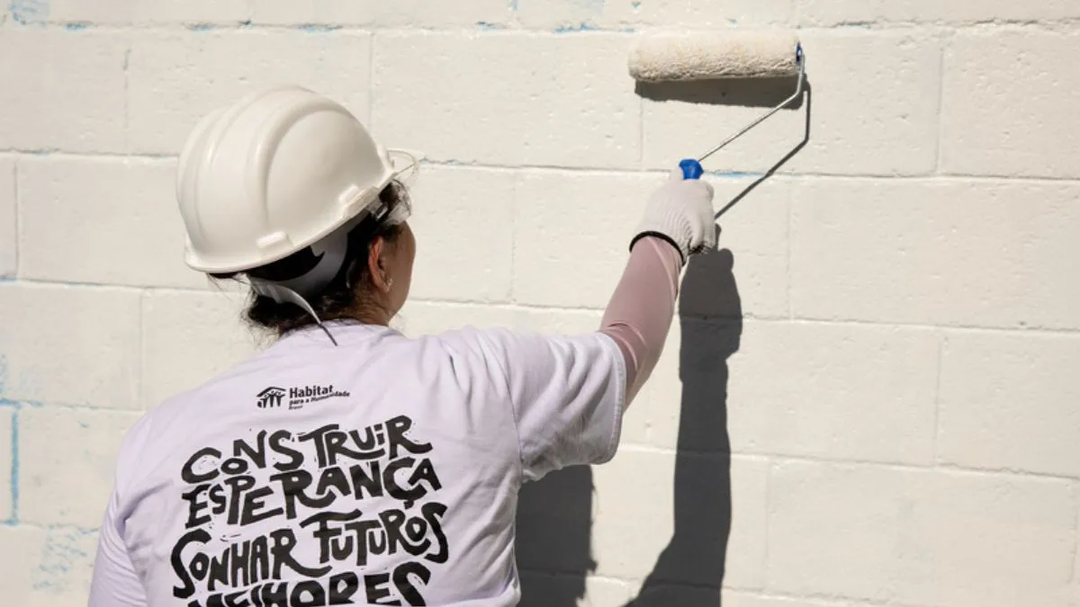 Voluntários trabalham juntos durante ação de melhoria em moradia de família atendida por projeto social.