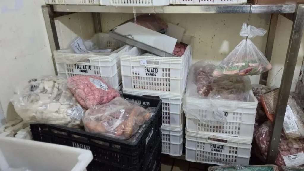 Carnes e alimentos armazenados em caixas plásticas e embalagens dentro de açougue fiscalizado em Indaiatuba, onde cerca de 350 kg de produtos impróprios foram apreendidos.