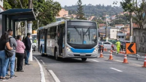 Ônibus municipal circula por rua de Perus durante alteração temporária de trânsito, com passageiros aguardando no ponto