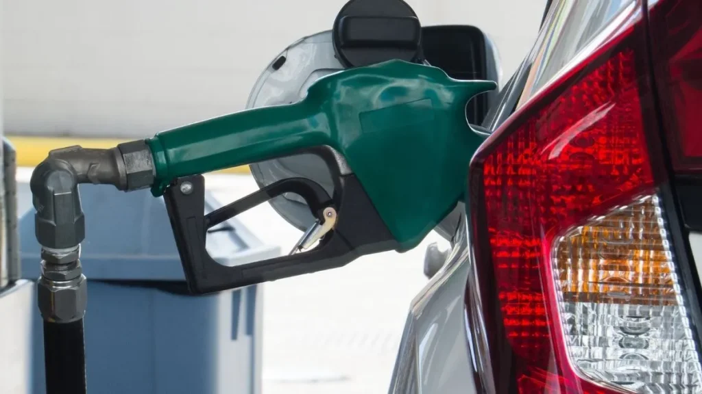 Bico de abastecimento verde inserido no tanque de um carro em posto de combustíveis, ilustrando a discussão sobre o aumento do ICMS da gasolina e seus possíveis efeitos sobre o preço do etanol em 2027.