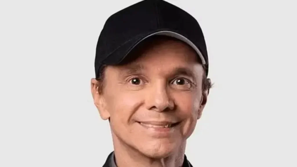 Netinho morre aos 60 anos e deixa trajetória marcada pelo axé, carnaval e sucessos que atravessaram gerações 4 Retrato do cantor Netinho usando boné preto e sorrindo diante de fundo claro