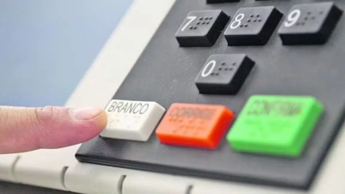Eleitor pressiona a tecla branca de uma urna eletrônica durante a votação.